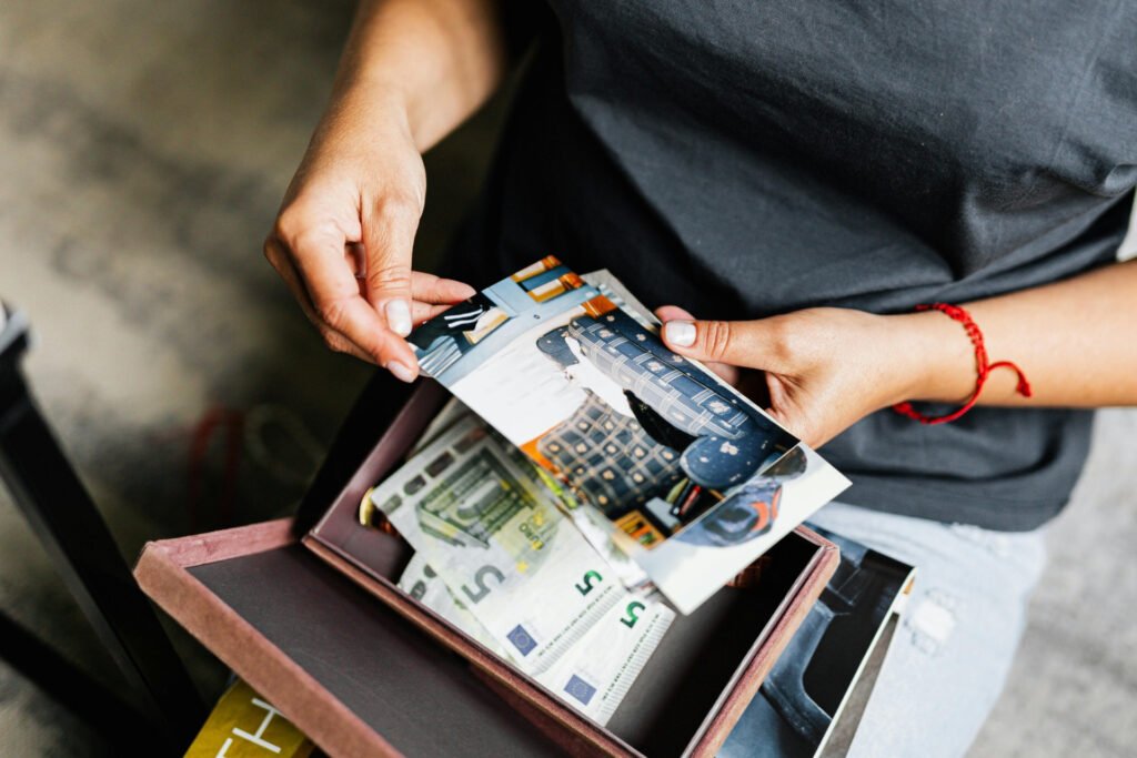 Hands sorting through a memory box filled with printed keepsakes, photos, and mementos