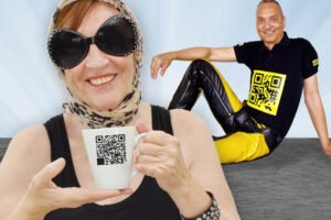 Smiling woman holding a coffee mug with a QR code, seated man wearing a shirt with a bright yellow QR code design, playful concept photo.