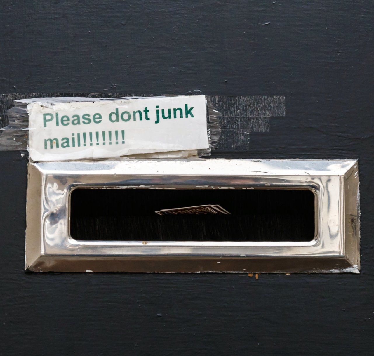 Mail slot with a handwritten “Please don’t junk mail” sign taped above it, illustrating how modern direct mail marketing avoids the old junk-mail approach.