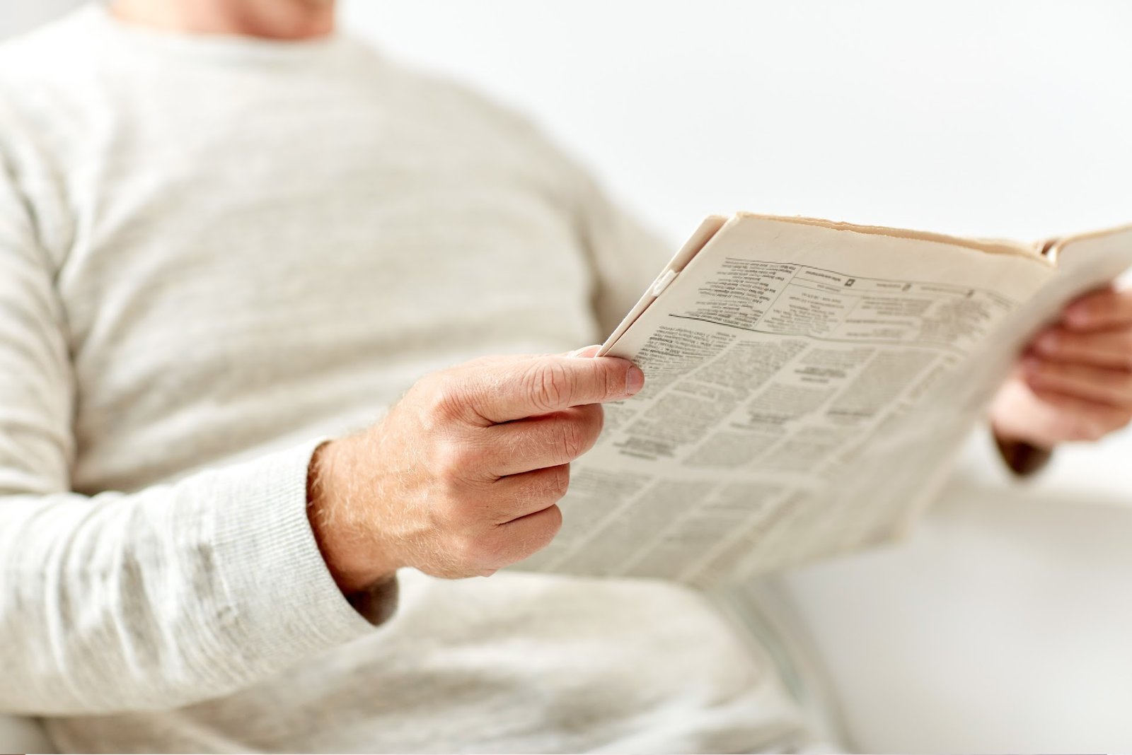 Person reading a printed newspaper, illustrating print media credibility and trust in physical communication