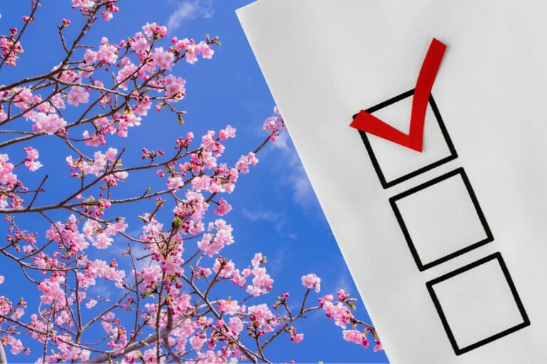 Pink spring blossoms beside a checklist with a red check mark against a bright blue sky